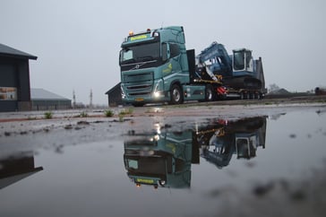 Elektrische vrachtwagen met bouwmachine weerspiegeling
