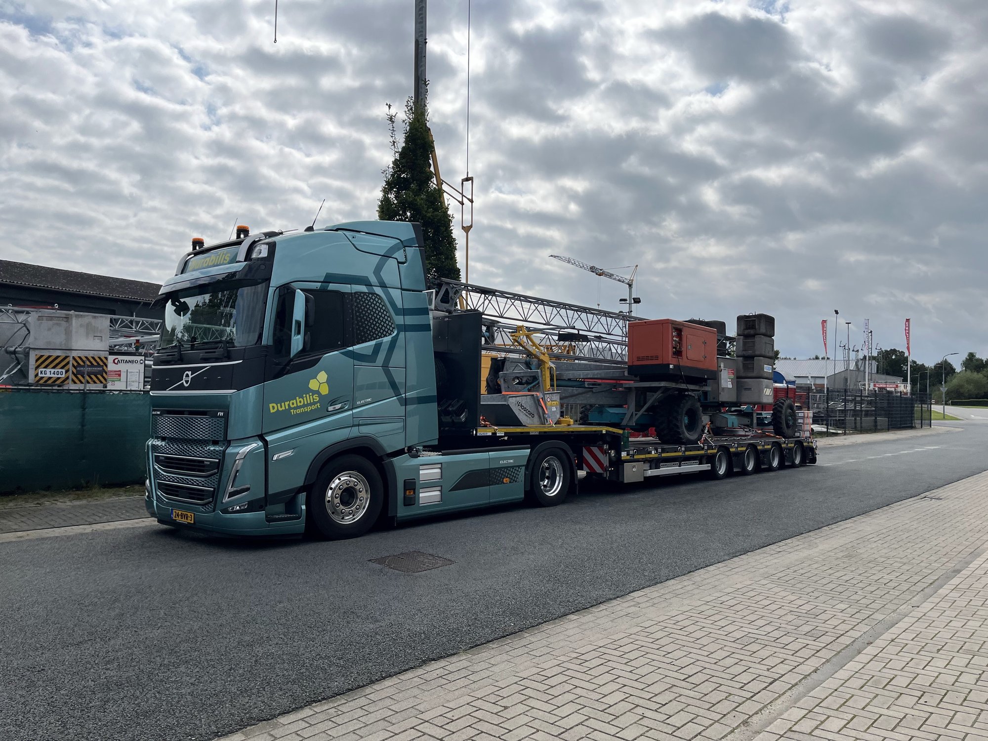 Elektrische vrachtwagen zijkant met bouwmachine