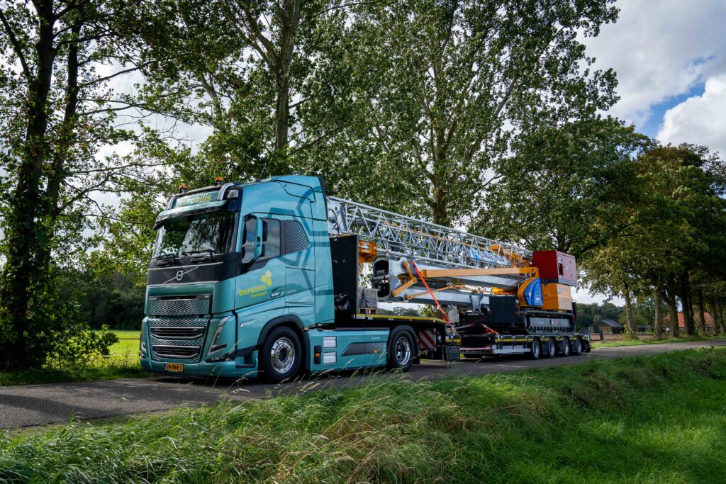 Elektrische vrachtwagen onderweg met bouwmachine